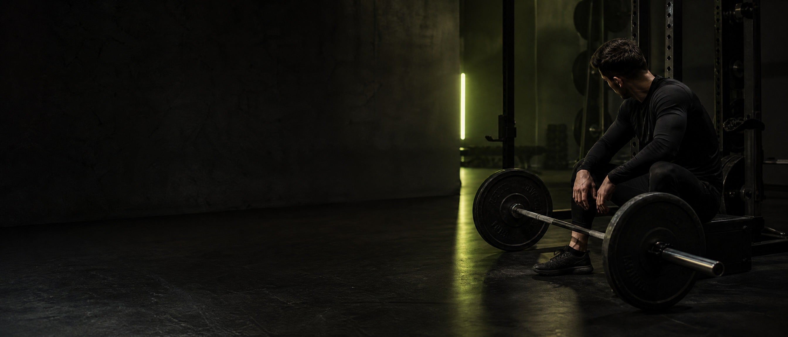 Athlete resting beside a barbell in a gym